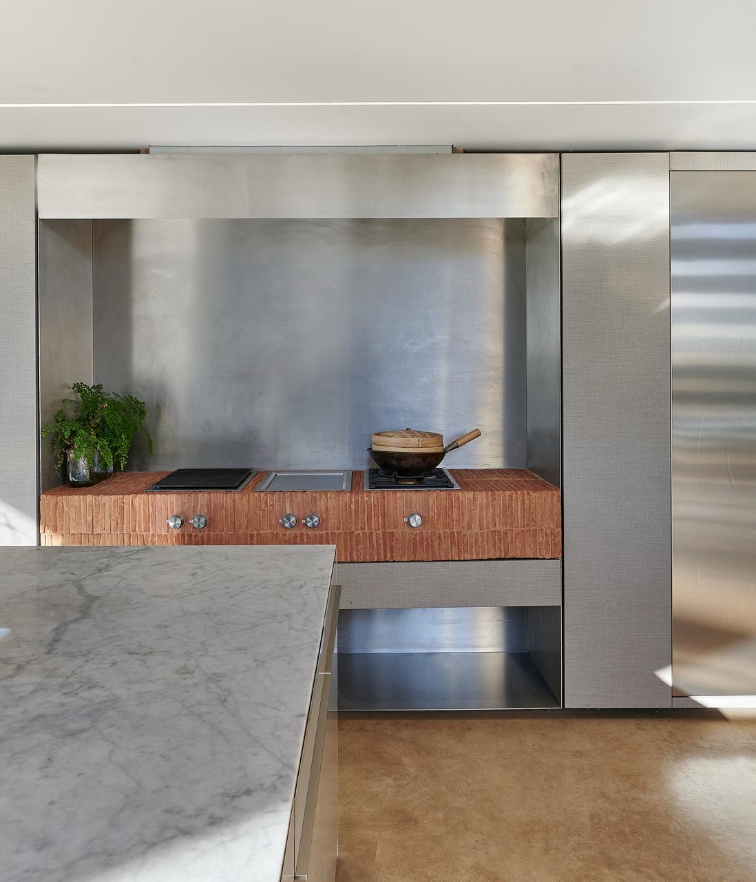 Bespoke kitchen with stainless steel cooking alcove and honed marble island