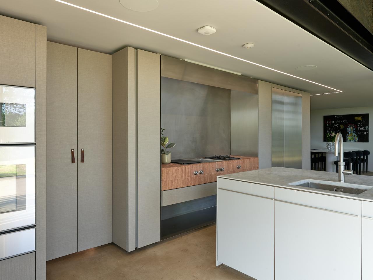Bespoke kitchen joinery in linen-textured cabinetry with concealed storage