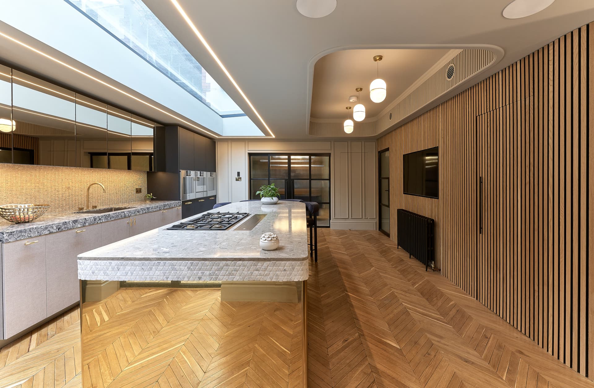 The Townhouse — kitchen with terrazzo island, brass base and chevron parquet under a skylight